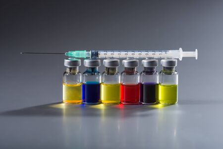 Ampoules in a row with syringe and needle on top symbolizing research activity.の写真素材