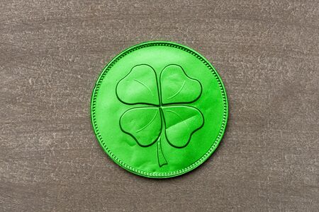 Green chocolate coin with four-leaf clover, wish you luck