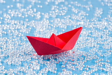Red Origami paper ship on blue waterlike background.の写真素材