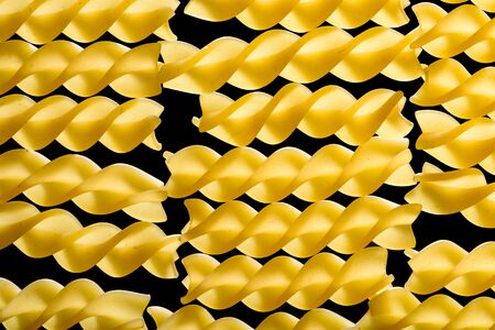 Spiral pasta noddles in several rows isolated on black background.の写真素材