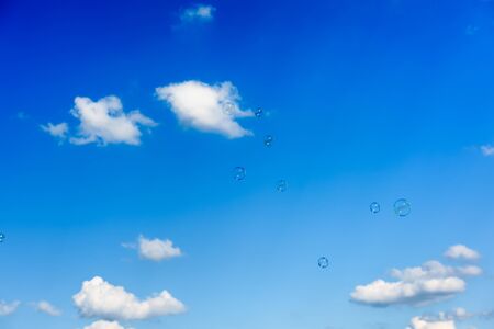 A bunch of soap bubbles flying up into the dark blue sky.の写真素材