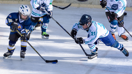 Fuerstenfeldbruck, Bavaria, Germany - 06. February 2016: German Kids playing ice hockey. Age is about 10 years. Player with white shirt on the right is trying a last minute defense action.のeditorial素材