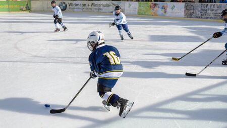 Fuerstenfeldbruck, Bavaria, Germany - 06. February 2016: German Kids playing ice hockey. Age is about 10 years. Blue player starting a long run to the goal.のeditorial素材