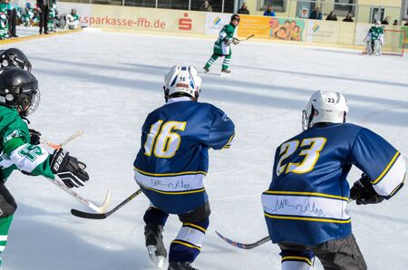 Fuerstenfeldbruck, Bavaria, Germany - 06. February 2016: German Kids playing ice hockey. Age is about 10 years. Close up of two blue players rushing to the goal.のeditorial素材