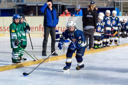 Fuerstenfeldbruck, Bavaria, Germany - 06. February 2016: German Kids playing ice hockey. Age is about 10 years. Blue Player is apporaching the goal from the sideline.のeditorial素材