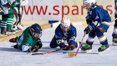 Fuerstenfeldbruck, Bavaria, Germany - 06. February 2016: German Kids playing ice hockey. Age is about 10 years. Players went to the ground, but are still fighting for the puck.のeditorial素材