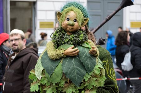 MUNICH, BAVARIA, GERMANY -  MARCH 13, 2016: Close up on woman hiding behind a green goblin doll at...