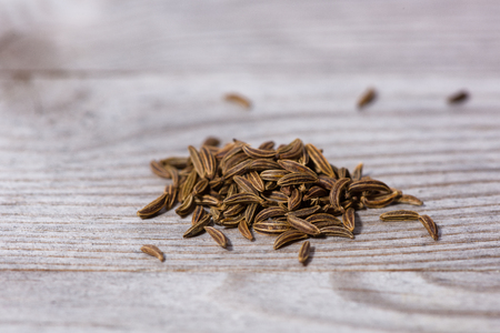 Pile of caraway seeds on wooden cutting board.の写真素材