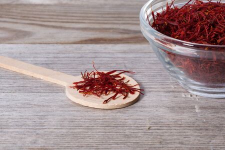 Close up on spoon with red saffron on wooden cutting board.の写真素材