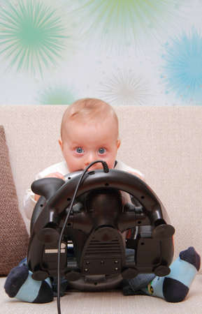 baby on couch with computer-game deviceの写真素材