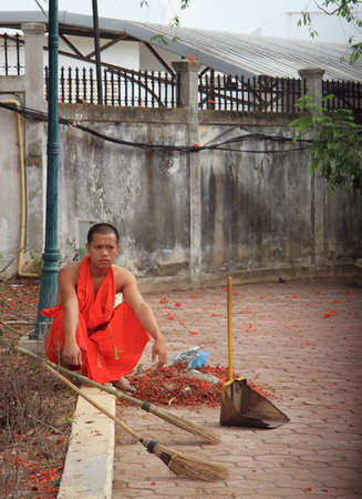 Vientiane, Laos - May 16, 2015 buddist monk is resting after the street cleaning, Vientianeのeditorial素材