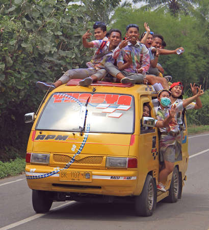 Medan, Indonesia - April 15, 2015 students are going to celebrate of finishing of school and moving to tourist place in the van - someone even on the roof of vanのeditorial素材
