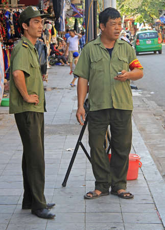 Hanoi, Vietnam - June 1, 2015: two vietnamese policemen are watching what happen on the streetsのeditorial素材