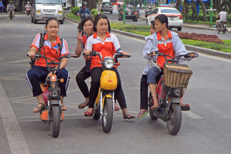 Hanoi, Vietnam - June 2, 2015: vietnamese girls are riding somewhere by motorcycle