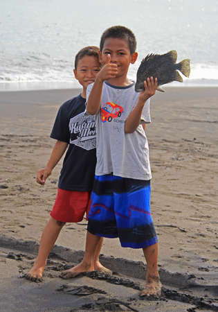 Kuta, Indonesia - April 28, 2015: two boys are showing fish that they tookのeditorial素材