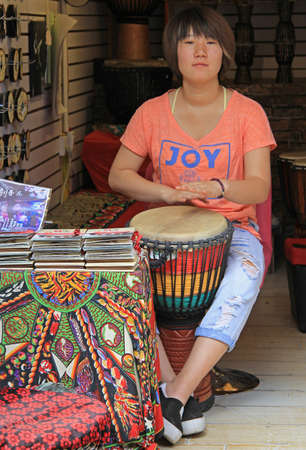 Lijiang, China - June 10, 2015: woman is playing drum on the street in Lijiang, Chinaのeditorial素材