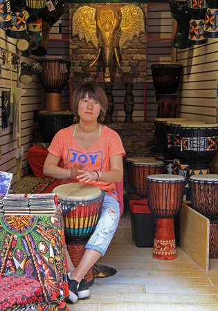 Lijiang, China - June 10, 2015: woman is playing drum on the street in Lijiang, Chinaのeditorial素材