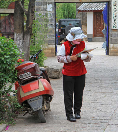 Lijiang, China - June 10, 2015: woman is reading something in the street in Lijiang, Chinaのeditorial素材