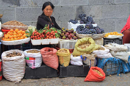 Lijiang, China - June 10, 2015: woman is selling fruits and spicery on the market in Lijiang, Chinaのeditorial素材