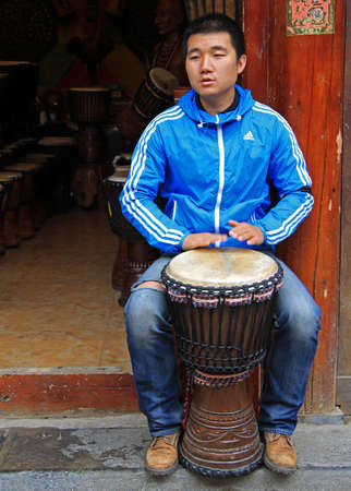 Lijiang, China - June 11, 2015: man is playing djembe on the street in Lijiang, Chinaのeditorial素材