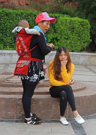 Lijiang, China - June 11, 2015: mother with older daughter and baby are waiting someone on the street in Lijiang, Chinaのeditorial素材