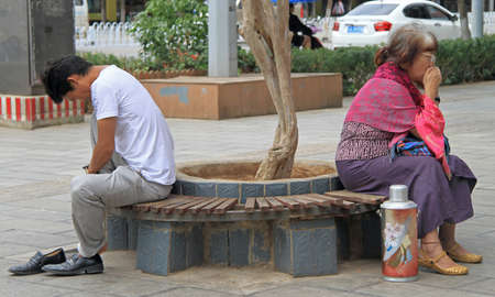 Kunming, China - June 8, 2015: man and woman are sitting on the bench in park, Kunming, Chinaのeditorial素材
