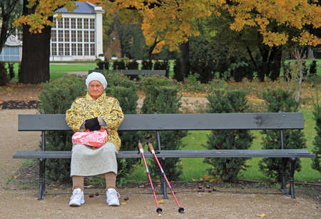 Warsaw, Poland - October 23, 2015: old woman with crutches is sitting on a bench in park of Warsaw,Polandのeditorial素材