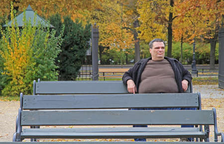 Warsaw, Poland - October 23, 2015: fat man is sitting on a bench in park of Warsaw, Polandのeditorial素材