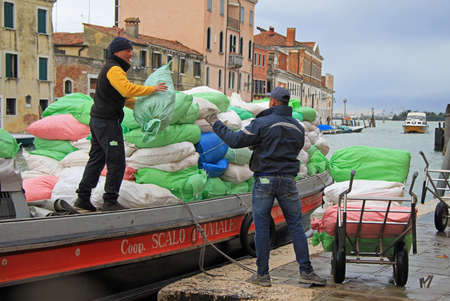 Venice, Italy - November 23, 2015: two men are unloading sacks from the boat in Venice, Italyのeditorial素材