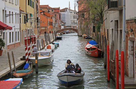 Venice, Italy - November 23, 2015: two men are riding in boat by the narrow water canal in Venice, Italyのeditorial素材