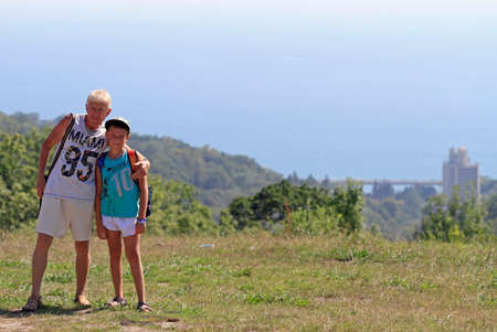 boy with grandfather at the hill against background of black seaの写真素材