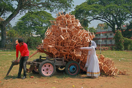 Kochi, India - March 7, 2015: man and woman are unloading a cart with cargo of stools outdoor in Kochi, Indiaのeditorial素材