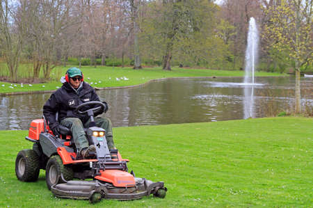 worker is cutting grass on lawn mower in parkのeditorial素材