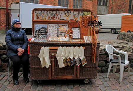 woman is selling souvenirs and warm clothes outdoor in Riga, Latviaのeditorial素材