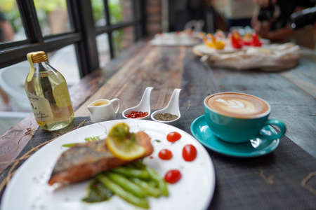 A coffee cups with coffee latte and delicious salmon for breakfast at the cafe