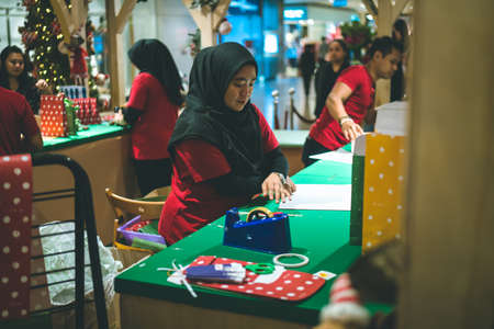 Kuala Lumpur, Malaysia - December 2020: Preparing for Christmas. Young Asian hands pack a giftのeditorial素材