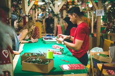 Kuala Lumpur, Malaysia - December 2020: Preparing for Christmas. Young Asian hands pack a giftのeditorial素材