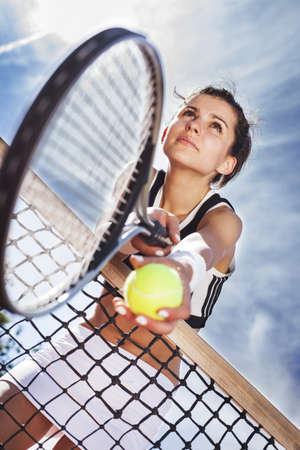 beautiful young girl rests on a tennis net on the skyの写真素材