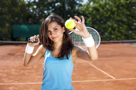 Young, beautiful girl on the tennis court on a beautiful sunny dayの写真素材