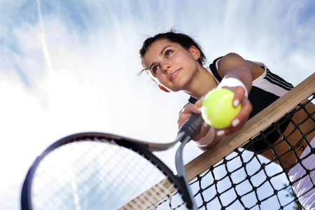 beautiful young girl rests on a tennis net on the skyの写真素材