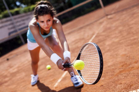 Young, beautiful girl on the tennis court on a beautiful sunny dayの写真素材