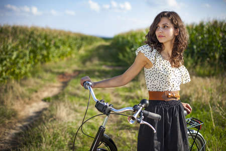 Pretty girl with bike on grassの写真素材