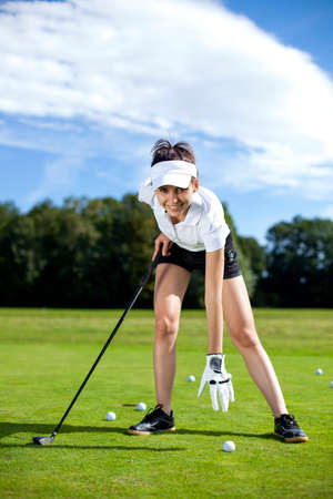 Pretty girl playing golf on grass in summerの写真素材