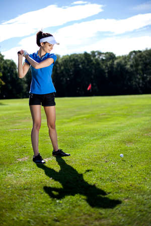 Pretty girl playing golf on grass in summerの写真素材