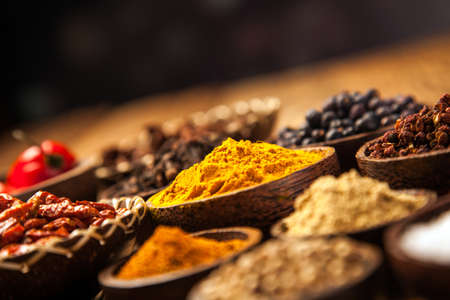 A selection of various colorful spices on a wooden table in bowls