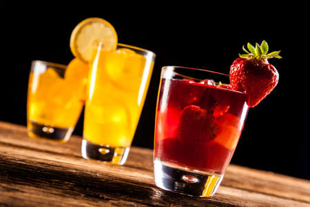 Fresh tasty drinks on black background with fruitsの写真素材