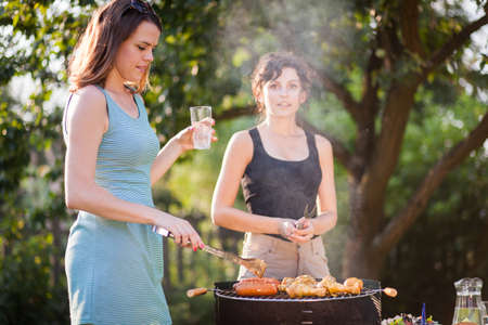 Two pretty girls making food on grillの写真素材