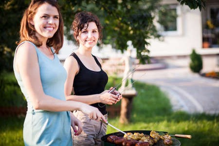 Two pretty girls making food on grillの写真素材