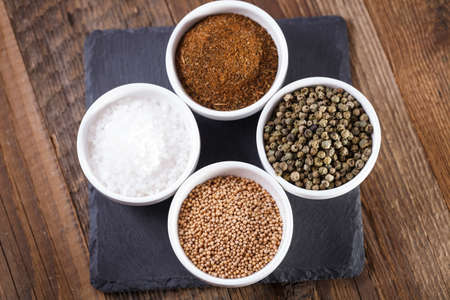 Aromatic spices in white bowls on a wooden tableの写真素材