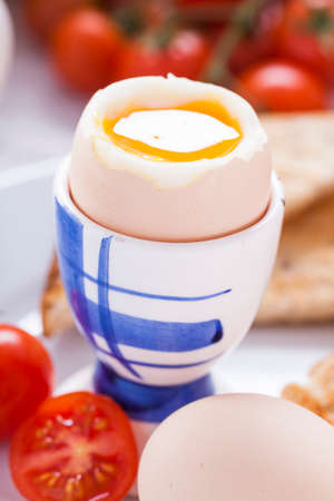 Soft-boiled egg in the morning with toast. In the background of the jam, coffee, tomatoes and snap....